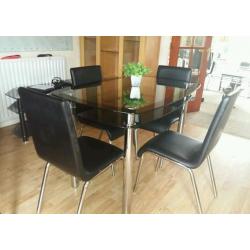 glass table (80 cm x 120 cm) with chrome legs. with 4 black leather chairs with chrome legs.