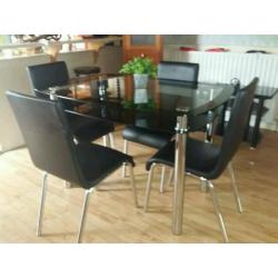 glass table (80 cm x 120 cm) with chrome legs. with 4 black leather chairs with chrome legs.